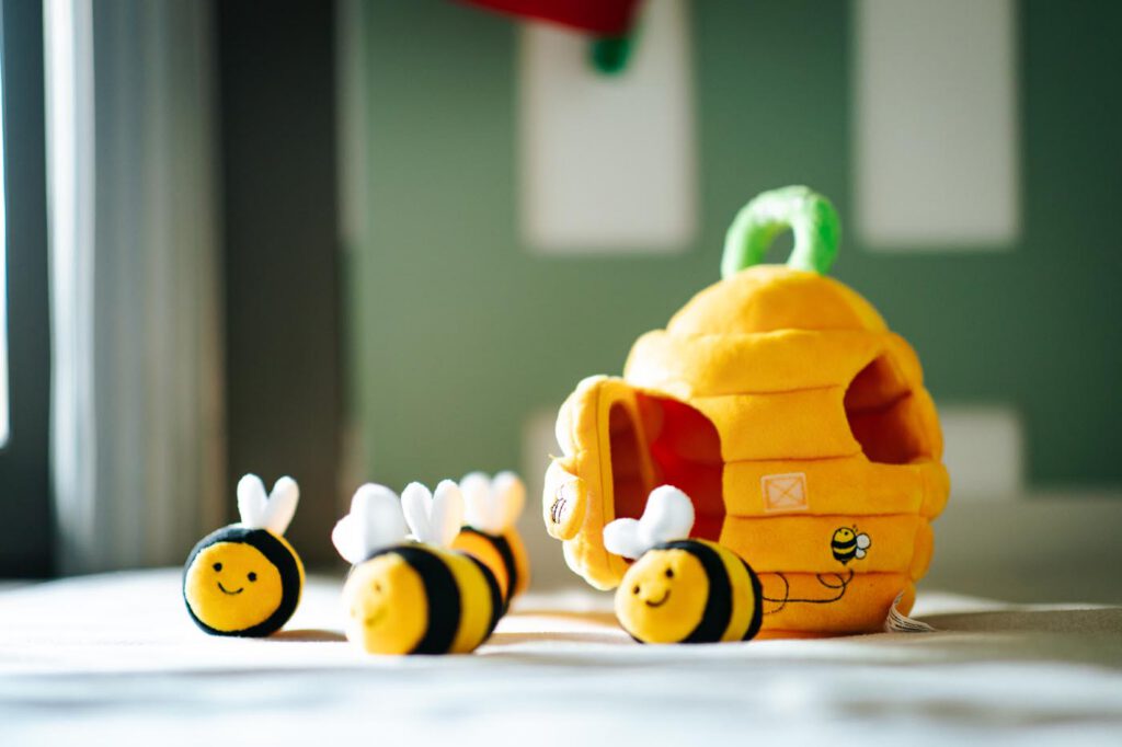 Abeilles jouets autour d'une ruche en peluche jaune.